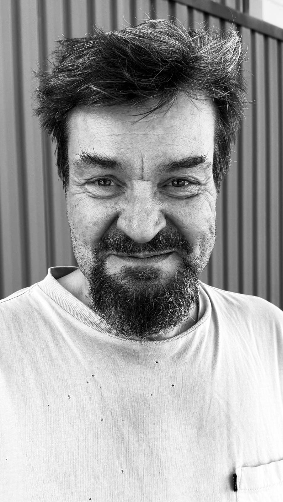 Mustavalkoinen lähikuva parrakkaasta miehestä rennossa paidassa
